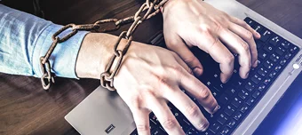 Mãos presas com corrente e cadeado a um notebook