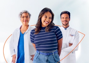 Três pessoas sorrindo, representando o modelo de saúde integrado da Hapvida, uma médica, uma paciente e um médico, lado a lado.