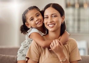 Mãe sorrindo com filha no colo, simbolizando acolhimento e compromisso da Política da Qualidade Hapvida com excelência no atendimento.